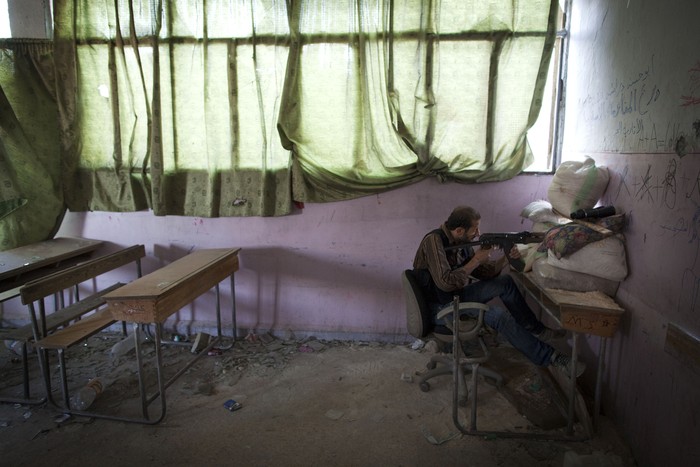 Một tay súng nổi dậy ngắm bắn lực lượng chính phủ Syria trong một trường học bị phá hủy ở quận Izaa, Aleppo, vào ngày 14/7.