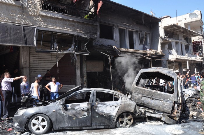 Người Syria tập trung gần chiếc xe bị hư hỏng sau khi một bom xe phát nổ ở ngoại ô Jaramana, Damascus, Syria ngày 25 tháng 7.