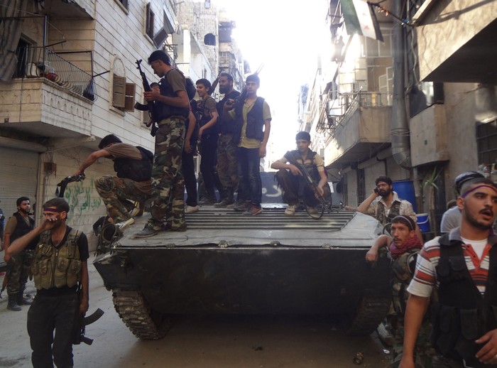 Chiến binh nổi dậy tập trung xung quanh một chiếc xe tăng của quân đội Syria sau trận chiến tại khu phố Salaheddine, Aleppo ngày 8/7.