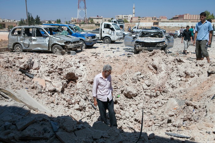 Người dân xem xét hố bom tại Saraqeb ở tây bắc Syria vào ngày 20 tháng 7.