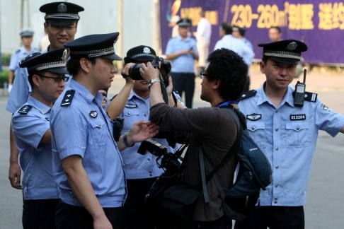 Cảnh sát ngăn chặn một phóng viên ảnh từ chụp ảnh bên ngoài Tòa án nhân dân Tế Nam