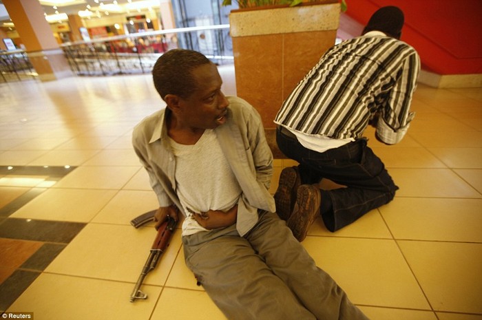 Một cảnh sát Kenya ôm bụng bị thương trong khi người khác đang tìm cách thương thuyết với các tay súng.