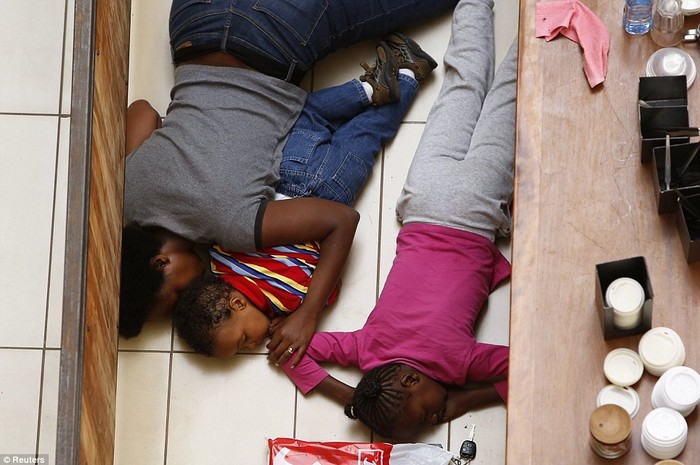 Một người mẹ và 2 đứa con của mình nằm trên sàn nhà khi họ cố gắng trốn các tay súng được trang bị vũ khí tự động đang nổi cơn thịnh nộ