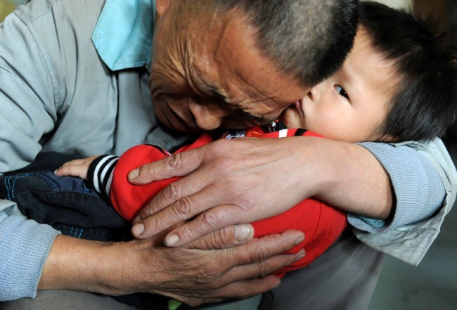 Wang Bangyin, một nông dân Trung Quốc ôm cậu con trai được giải thoát từ tay những kẻ bắt cóc, buôn người tại Trung tâm Phúc lợi trẻ em Quý Dương, Quý Dương, tỉnh Quý Châu. (Ảnh Reuters)