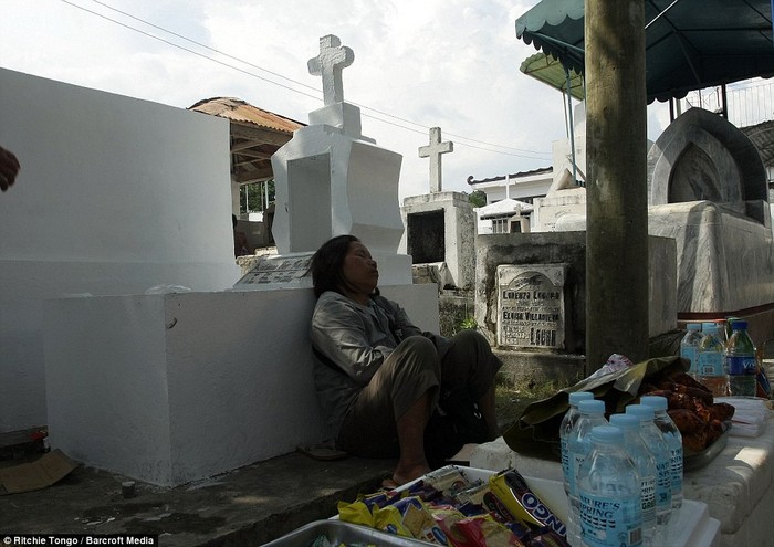 Một người Philippines có giấc ngủ ngắn trong khi đi viếng những người đã khuất vào ngày lễ.
