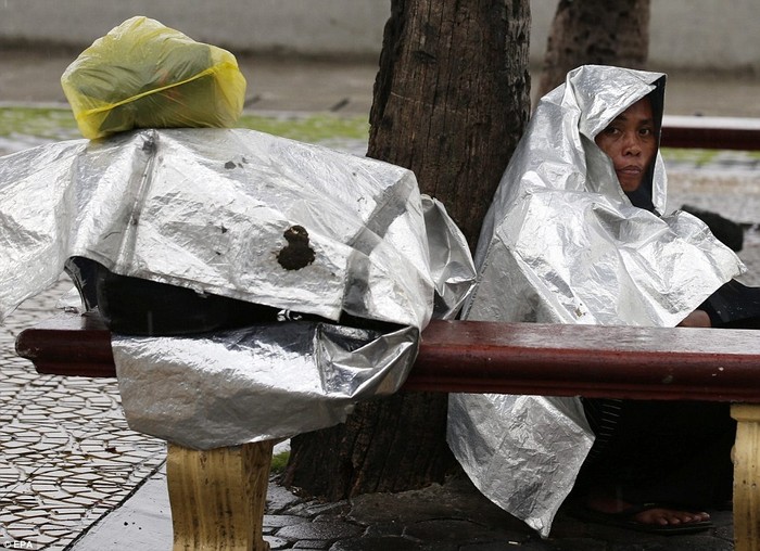 Một người dân Manila ngồi co ro trong mưa bão.