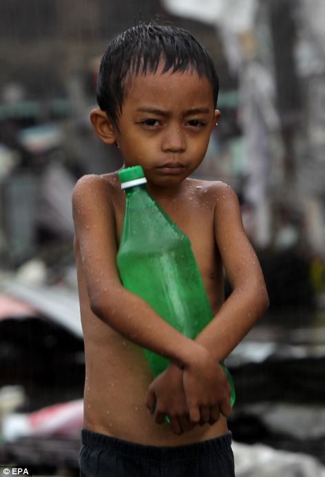Một cậu bé Philippines co ro trong mưa lớn hậu siêu bão Haiyan.