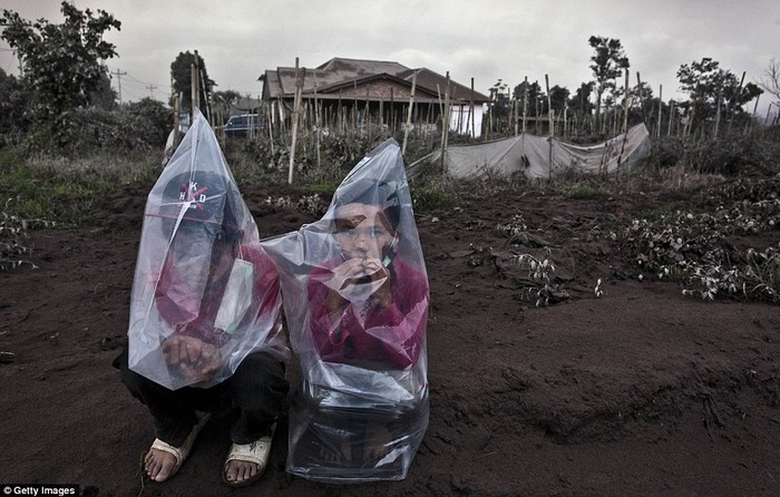 Hai em bé Indonesia trùm túi bóng để tránh tro và khói từ núi lửa.