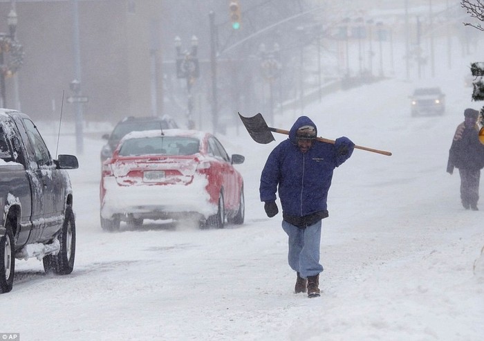 Một người đàn ông ở Flint, Michigan, mang xẻng của mình khi đi bộ trên tuyết.