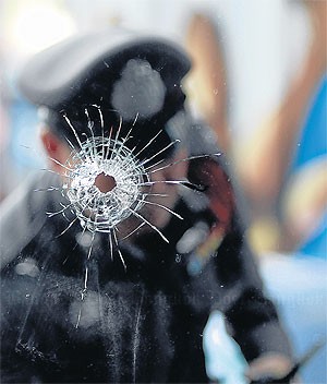 Cảnh sát Thái Lan sau tấm kính bị đạn xuyên thủng.