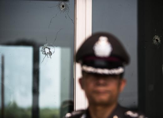 Cảnh sát đứng gần cửa cổ lỗ chỗ đạn của nhà ông Kwanchai.
