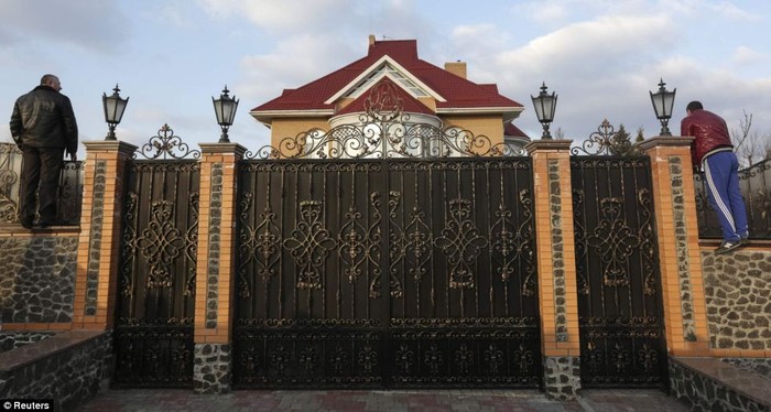 Hai người đàn ông nhìn qua cánh cổng vào bên trong dinh thự sang trọng của ông Yanukovych.