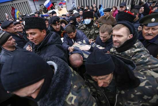 Người biểu tình ủng hộ Nga hộ tống một người đàn ông bị bắt vì cố gắng bán một khẩu súng lục cạnh cơ quan an ninh SBU ở Luhansk.