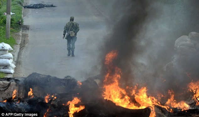 Một người đàn ông vũ trang ủng hộ Nga đi qua trạm kiểm soát bị đốt cháy gần Salviansk.