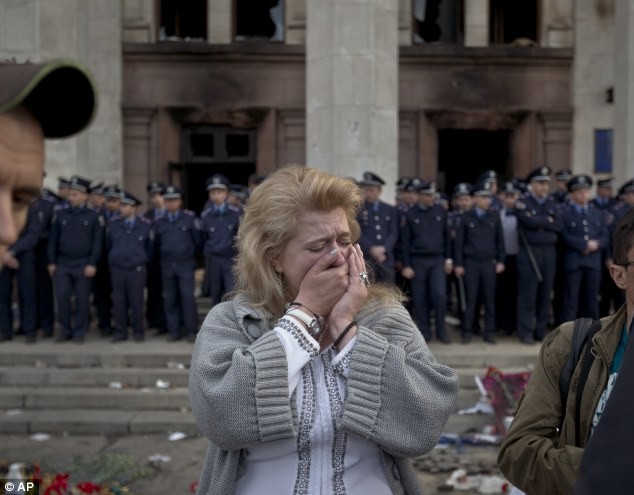 Một phụ nữ khóc trước tòa nhà cháy khi cảnh sát đang bảo vệ phần còn lại của nó.