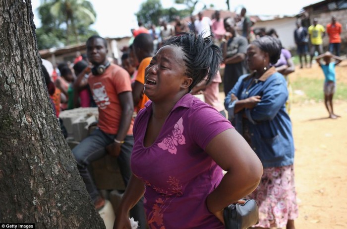 Một phụ nữ khóc như mưa trước khi mặc đồ bảo hộ để đưa em gái chết vì nhiễm Ebola ra ngoài.