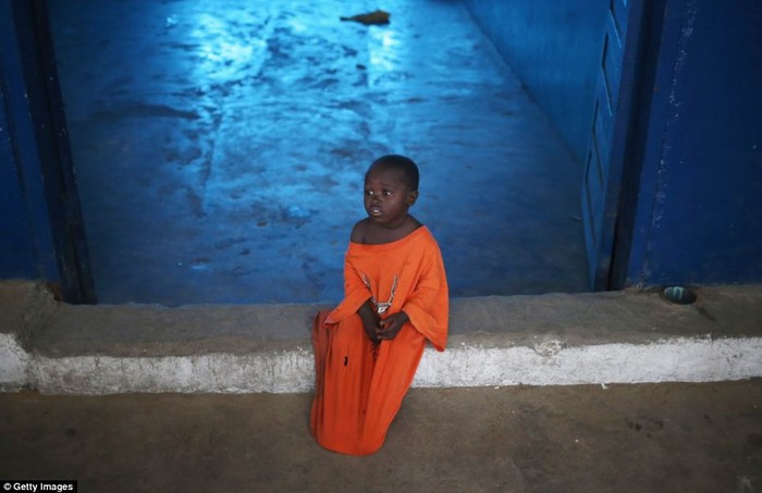 Nino, 3 tuổi, ngồi trong một trung tâm cách ly tại Liberia được thành lập trên cơ sở một trường học đã đóng cửa.