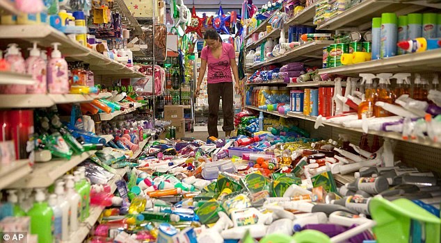 Một phụ nữ đứng thẫn thờ trước cảnh lộn xộn trong siêu thị.