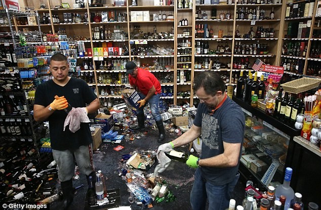 Nhân viên một cửa hàng rượu dọn dẹp sau trận động đất.