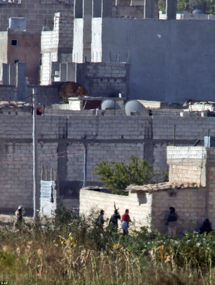 Các phần tử khủng bố IS ẩn sau một bức tường ở ngoại ô Kobani. Ảnh được chụp từ Thổ Nhĩ Kỳ bằng máy ảnh.