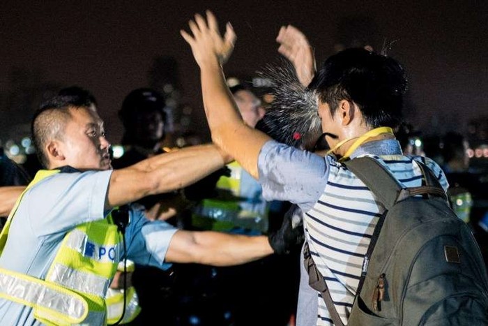 Một sĩ quan cảnh sát Hồng Kông xịt hơi cay vào một người biểu tình ủng hộ dân chủ khi đối mặt.
