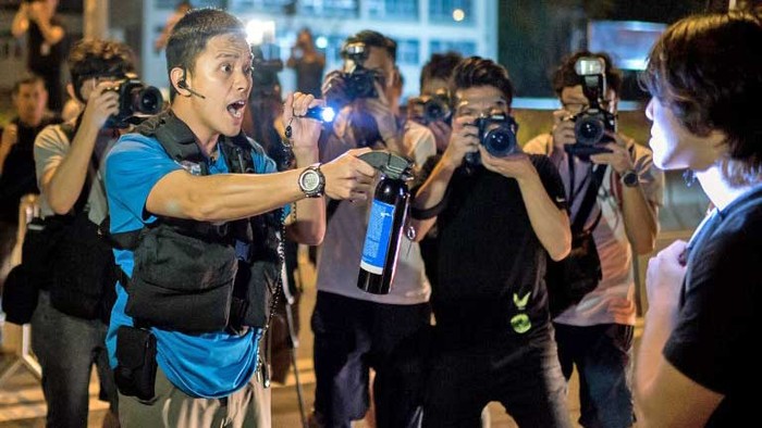 Một sĩ quan cảnh sát Hồng Kông đe dọa xịt hơi cay người biểu tình trên một con phố chính ở trung tâm thành phố.