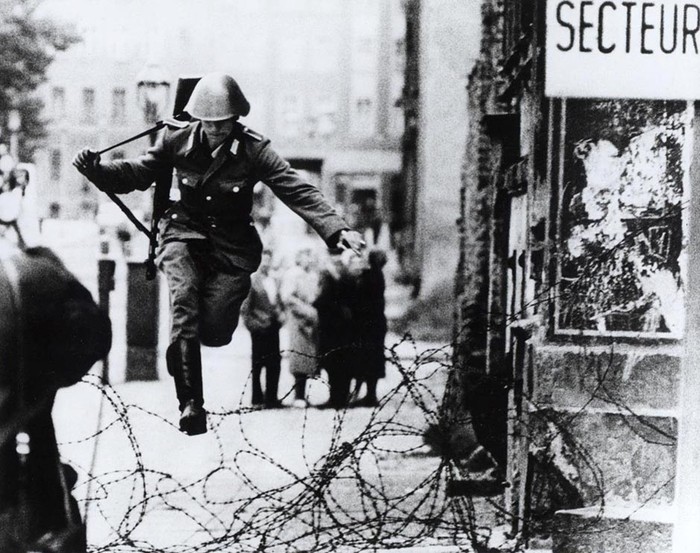 Lính Đông Đức nhảy qua hàng rào kẽm gai khi bắt đầu xây dựng bức tường.