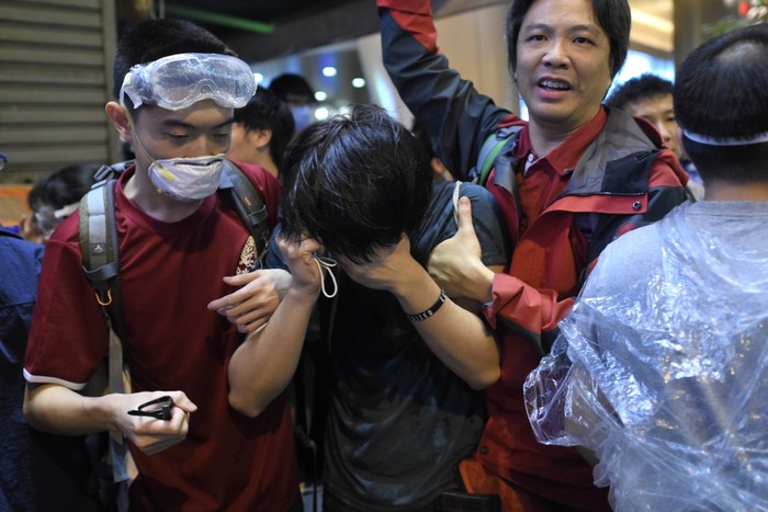 Người biểu tình ôm mặt sau khi bị trúng hơi cay.
