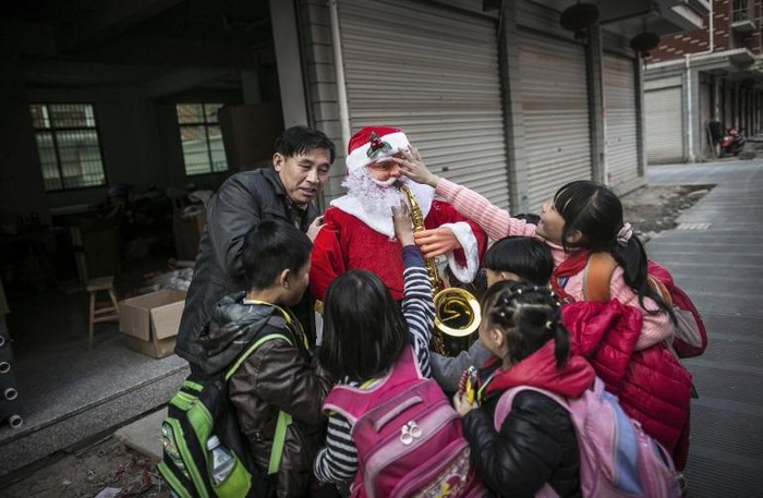 Trẻ em Yiwu chơi đùa với một ông già Noel bằng nhựa.