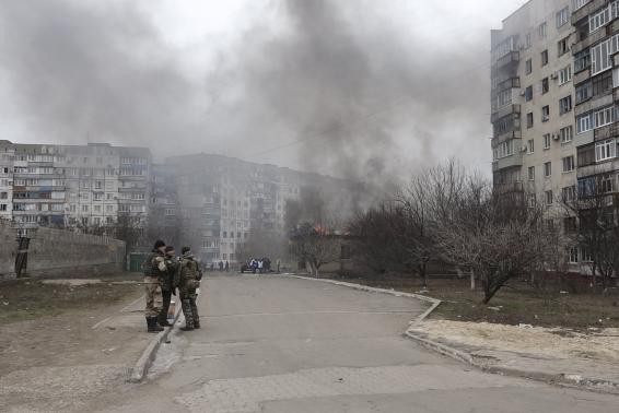 Lực lượng an ninh Ukraine đứng trước tòa nhà cháy sau vụ tấn công của lực lượng ly khai tại Mariupol.