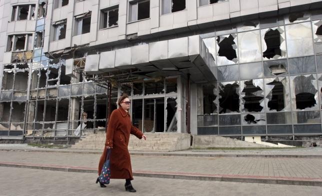 Một phụ nữ Ukraine đi qua tòa nhà bị hư hỏng nặng do các cuộc xung đột tại Donetsk. Ảnh Reuters.