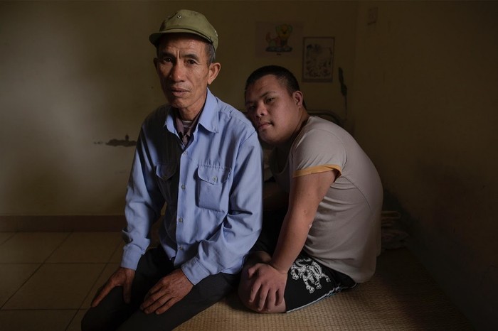 Cựu chiến binh Nguyễn Hồng Phúc, 63 tuổi, ngồi trên giường với con trai của ông Nguyễn Đình Lộc, 20 tuổi.