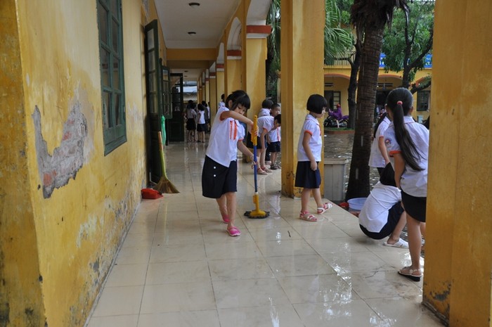 Một học sinh đang cố gắng đẩy nước ra khỏi lan can lớp học
