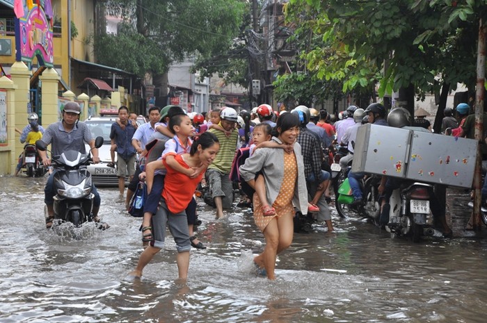 Nước mưa lẫn nước cống đen ngòm, bốc mùi khó chịu, nhưng người dân không còn cách nào khác là phải lội qua để di chuyển