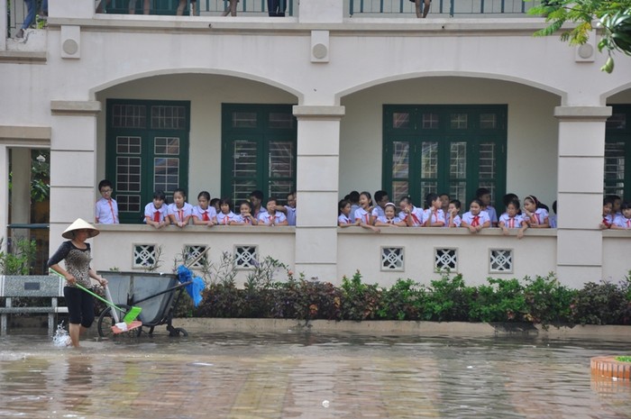 Mưa lớn gây ngập úng trong sân trường tiểu học Cổ Nhuế 2B. Các em học sinh tập trung ở lan can giờ nghỉ thay vì ra sân chạy nhảy như ngày thường.