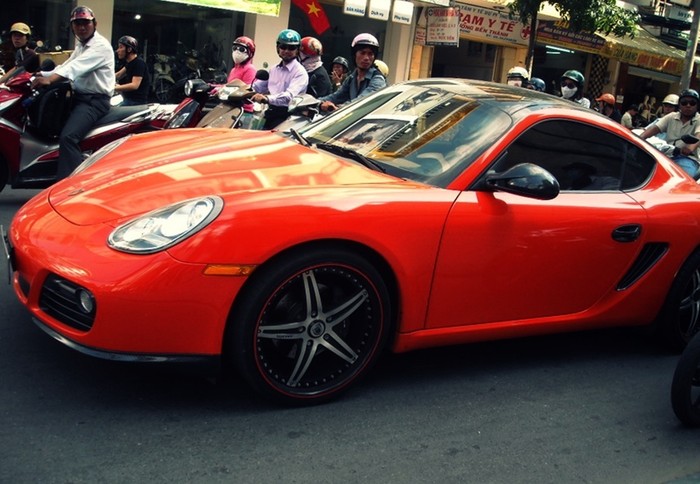 Chiếc Porsche màu cam nổi bật giữa phố thu hút mọi ánh nhìn.