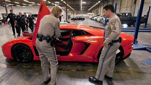 Hai thành viên của Cảnh sát giao thông California kiểm tra số xe của một chiếc Lamborghini Aventador LP700-4 2012. Những chiếc xe đắt tiền bị phát hiện khi chúng đã rời khỏi bến bốc dỡ với hóa đơn kê khai là "thiết bị tập luyện thể thao".