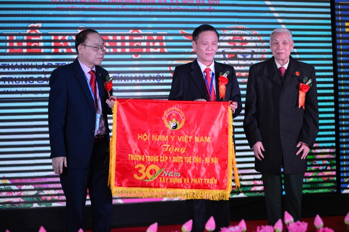 Lãnh đạo nhà trường nhận Cờ kỷ niệm 30 năm xây dựng và phát triển từ Hội Nam y Việt Nam. Ảnh: Trà My