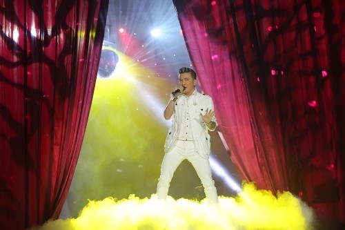 Ca sĩ Đàm Vĩnh Hưng trong bộ đồ trắng lịch lãm xuất hiện trên bục cao ở giữa sân khấu.