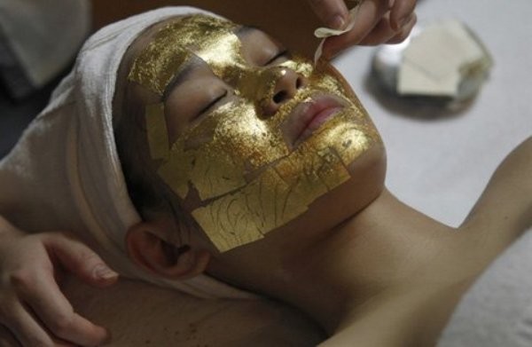 Một nhân viên đắp các lá vàng lên khuôn mặt của khách hàng tại thẩm mỹ viện Việt Mỹ hôm 13/2 (Ảnh: Reuters)