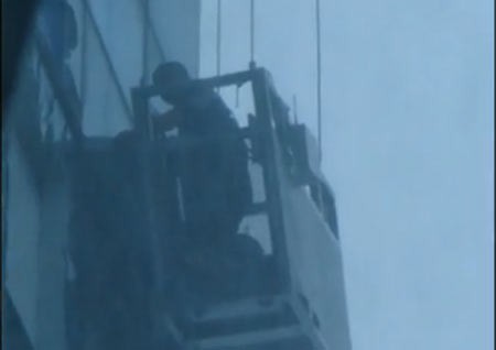 Các công nhân lau kính đang được đưa ra khỏi lồng sắt. Ảnh chụp từ clip.