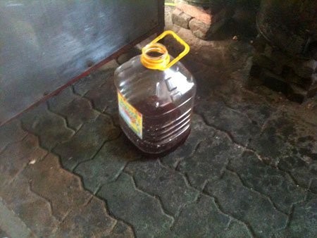 Dưới sàn nhà, một can dầu qua sử dụng đã dùng gần hết.