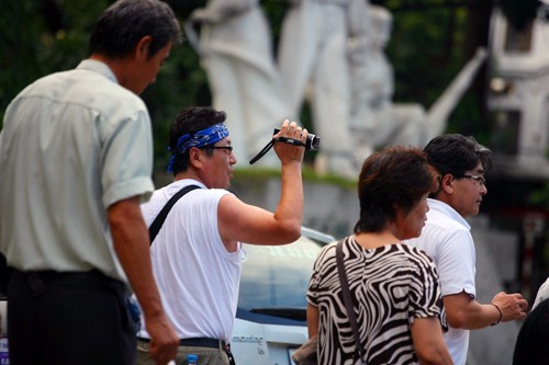 Một du khách người Nhật vừa đi, vừa cầm camera ghi lại hình ảnh xe cộ Hà Nội.