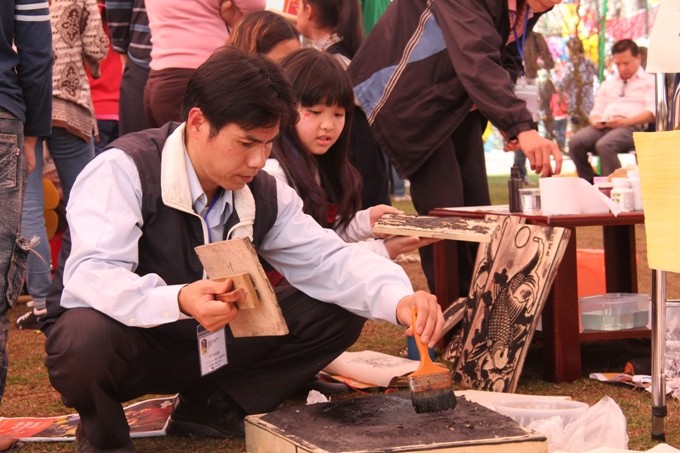 Gian hàng Tranh Đông Hồ không chỉ thu hút các em học sinh mà ngay cả người lớn cũng tìm hiểu cách làm tranh - một nghệ thuật dân gian nổi tiếng của Việt Nam.