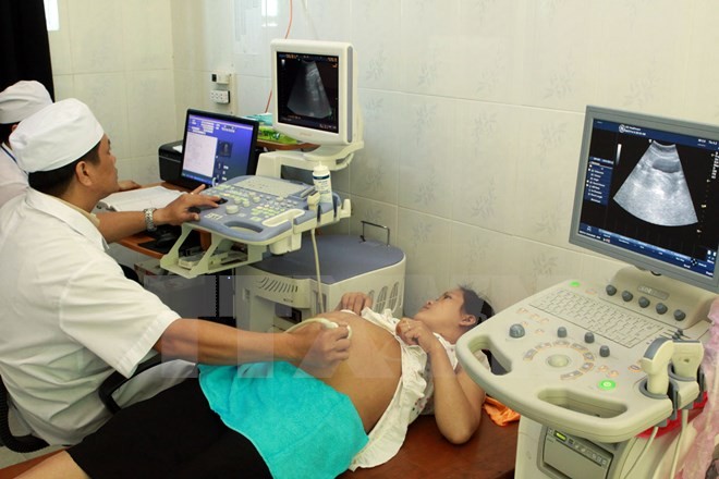 Nhân viên y tế kiểm tra sức khỏe cho một thai phụ. (Ảnh: TTXVN/Vietnam+).