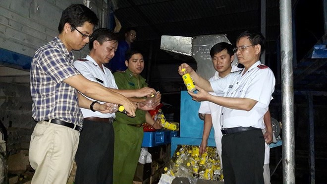 Đoàn thanh tra cùng đại diện Công ty URC Hà Nội giám sát việc tiêu hủy hàng không đạt chất lượng. (Ảnh: BYT cung cấp).