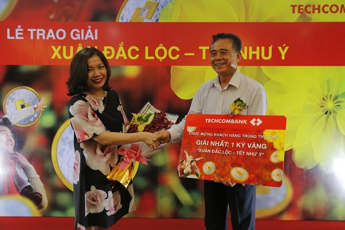 Bà Nguyễn Thị Vân Anh, Giám đốc Khối tiếp thị Techcombank trao giải Nhất 1kg vàng cho khách hàng Trần Đức Lợi.