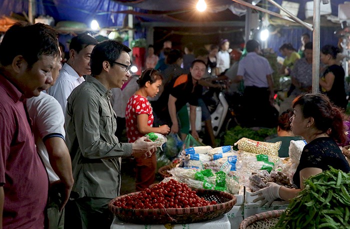 Phó Thủ tướng Vũ Đức Đam hỏi chuyện một tiểu thương buôn bán rau quả tại chợ Long Biên. Ảnh: VGP/Đình Nam.