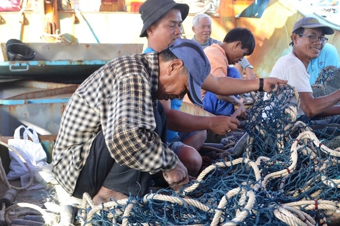 Ngư dân trên tàu vỏ thép Đna – 90777 TS của ngư dân Trần Văn Mười may vá lại ngư lưới cụ, chuẩn bị ra khơi. Ảnh: An Nguyên