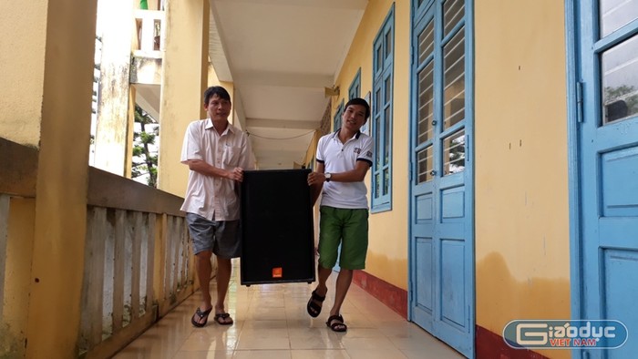 Hai thầy trường Tiểu học Quảng Phước mang loa về lại lớp sau khi được kê lên vì lũ.